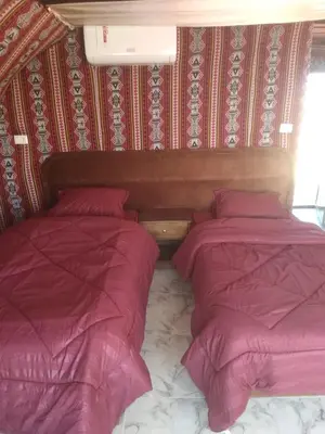 two beds in a room with pink comforter at Mujib Castle Gate Camp in Dhībān