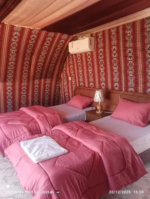 a bedroom with two beds with pink sheets and a wall at Mujib Castle Gate Camp in Dhībān