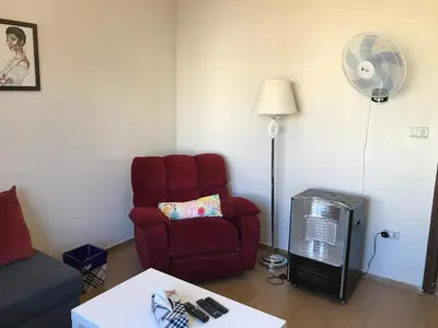 a living room with a red chair and a fan at Behind Mecca Mall in Amman