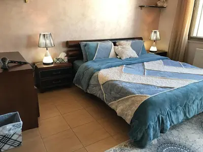 a bedroom with a bed with blue sheets and two lamps at Behind Mecca Mall in Amman