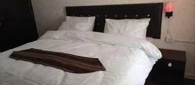 a large white bed with white sheets and pillows at Al Midan Hotel in Amman