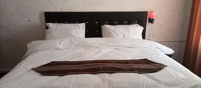 a white bed with a black headboard and white pillows at Al Midan Hotel in Amman