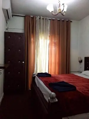 a bedroom with a red bed with a dresser and a window at Al Midan Hotel in Amman