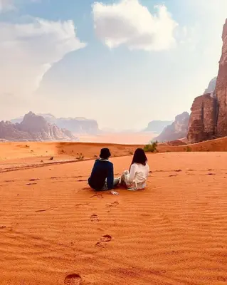 two people sitting on the sand in the desert at RUM SOlARIS BEDOUIN CAMP in Wadi Rum