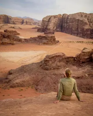 a person sitting on a rock in the desert at RUM SOlARIS BEDOUIN CAMP in Wadi Rum