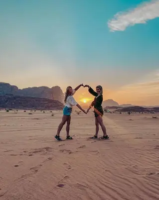 two women holding hands on a beach at sunset at RUM SOlARIS BEDOUIN CAMP in Wadi Rum