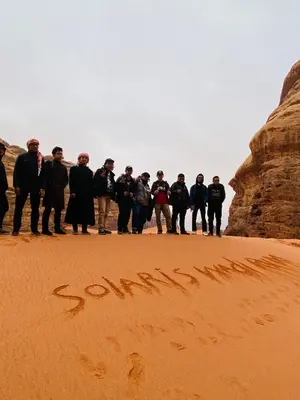 a group of people standing in the sand in the desert at RUM SOlARIS BEDOUIN CAMP in Wadi Rum