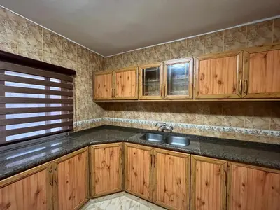 a kitchen with wooden cabinets and a sink at Sultan Home in Wadi Musa