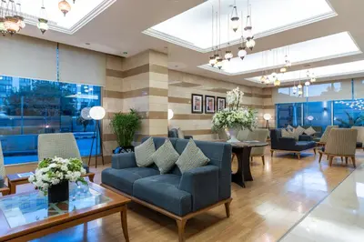 a lobby with a couch and tables and chairs at Corp Amman Hotel in Amman