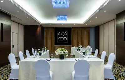 a meeting room with a table and white chairs at Corp Amman Hotel in Amman