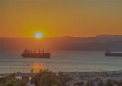 two ships in the ocean at sunset at Shweiki International Hotel in Aqaba