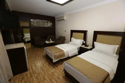 a hotel room with two beds and a chair at Al Zaitouna Hotel in Aqaba