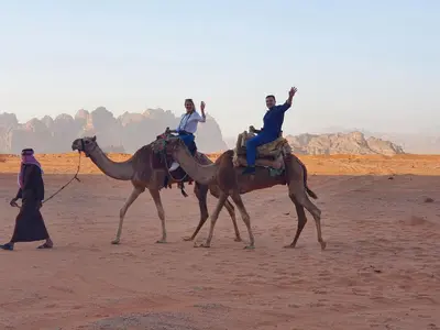 two people riding on the backs of camels in the desert at Desert Magic Camp & Resort in Wadi Rum