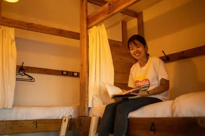 a woman sitting on a bed reading a book at The Cabin in Amman