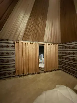 a bedroom with a wall with curtains and a window at North moon Camp in Wadi Rum