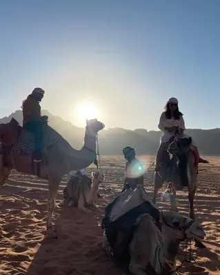 two people riding on camels in the desert at North moon Camp in Wadi Rum