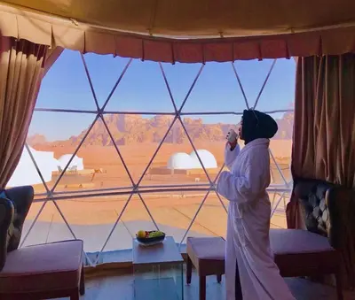 a woman talking on a cell phone in front of a window at Wadi Rum UFO Luxotel in Wadi Rum
