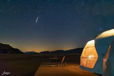 a tent with a table and chairs in the desert at Wadi Rum UFO Luxotel in Wadi Rum
