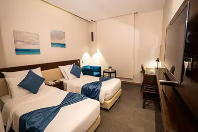 a hotel room with two beds and a desk at The Compass Hotel in Amman