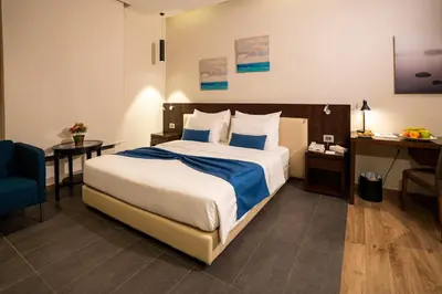 a hotel room with a bed and a blue chair at The Compass Hotel in Amman