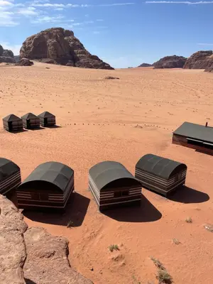 a group of beds sitting in the desert at Wadi Rum Old Bedouin Camp in Wadi Rum