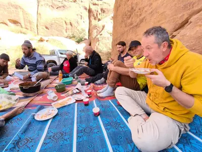 a group of people sitting around a table eating food at Wadi Rum Old Bedouin Camp in Wadi Rum