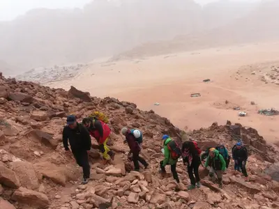 a group of people walking up a rocky mountain at Wadi Rum Old Bedouin Camp in Wadi Rum