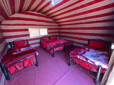 a room with three beds and a striped wall at Wadi Rum Old Bedouin Camp in Wadi Rum