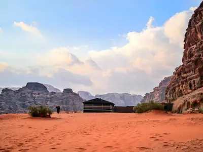 a person standing in the desert near a building in the desert at Wadi Rum Bright Moon in Wadi Rum