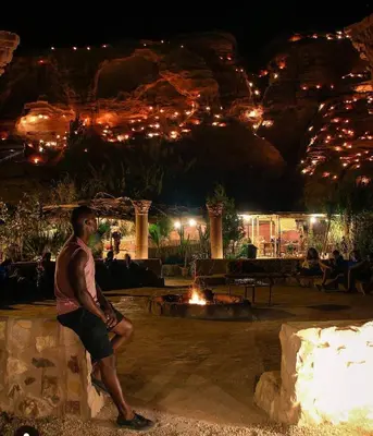 a man standing next to a fire pit at night at Seven Wonders Luxury Camp in Wadi Musa