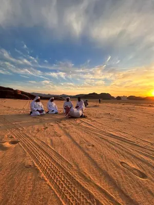 a group of people sitting in the desert at sunset at domes wadi Rum in Wadi Rum