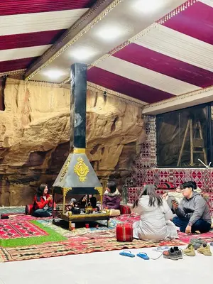 a group of people sitting on the floor around a fireplace at domes wadi Rum in Wadi Rum