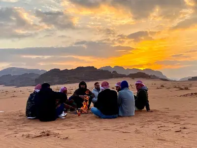 a group of people sitting around a fire in the desert at domes wadi Rum in Wadi Rum