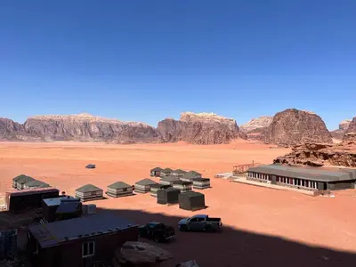 a building in the desert with mountains in the background at Wadi rum Silk Road camp in Wadi Rum