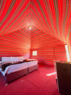 a bedroom with a red wall with a bed in it at Wadi rum Silk Road camp in Wadi Rum