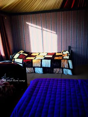 a bedroom with a bed and a wall with a window at Qais Camp Wadi Rum in Wadi Rum