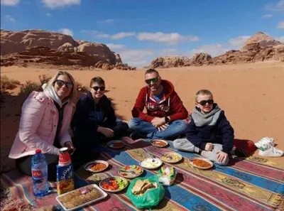 a group of people sitting around a picnic in the desert at Wadi rum Local guide camp in Wadi Rum