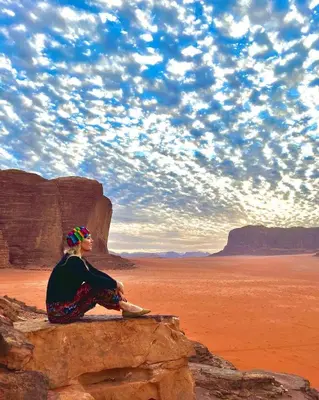 a woman sitting on a rock in the desert at Wadi rum Local guide camp in Wadi Rum