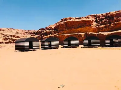 a group of three shelters in the desert at Wadi rum Local guide camp in Wadi Rum