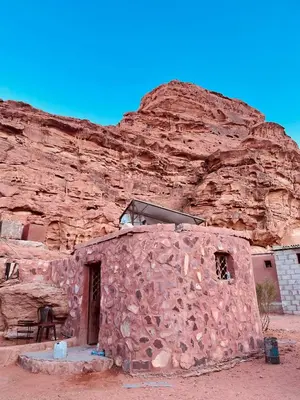 a small stone building in front of a mountain at Sunrise camp in Wadi Rum