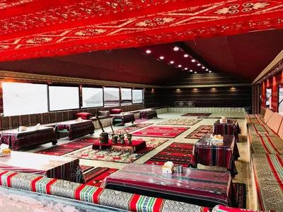 a large room with tables and couches and red ceiling at Wadi Rum Pyramids Camp in Wadi Rum