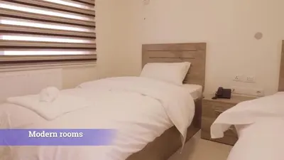 a bedroom with two white beds and a window at Al-Mujeb in Kerak