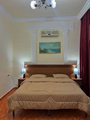 a bedroom with a large bed and two lamps at Sufara Hotel Suites in Amman