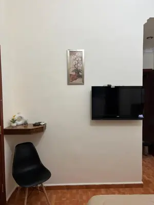 a flat screen tv on a white wall with a chair at Sufara Hotel Suites in Amman