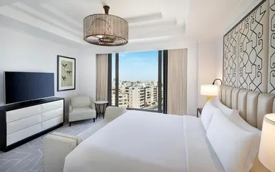 a bedroom with a white bed and a large window at The St. Regis Amman in Amman