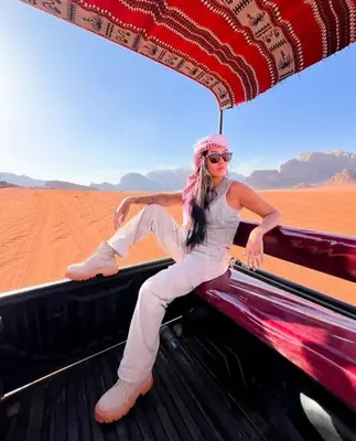 a woman sitting on the back of a truck in the desert at Moon city camp in Wadi Rum