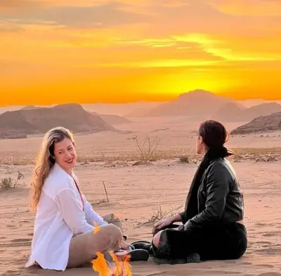 two women sitting on the sand in the desert at Moon city camp in Wadi Rum
