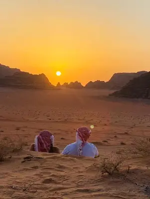 two people sitting in the desert watching the sunset at Moon city camp in Wadi Rum
