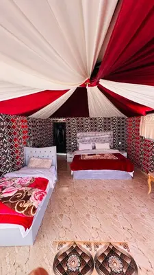 a bedroom with two beds and a large tent at Desert guide camp in Wadi Rum