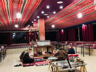 a group of people sitting in a room with a fireplace at wadi rum bedouin stars camp in Wadi Rum